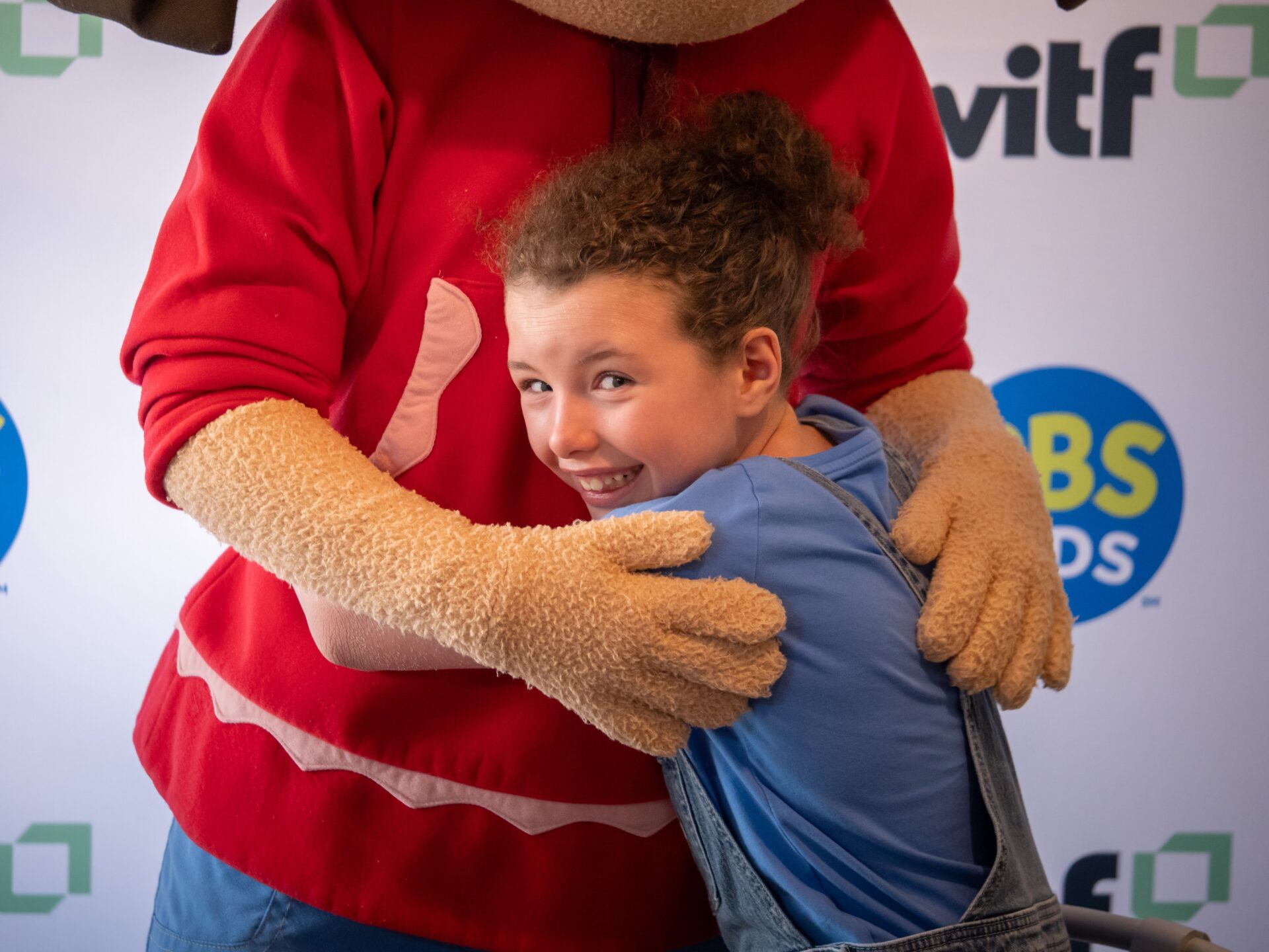 A child hugs a character at a WITF event.